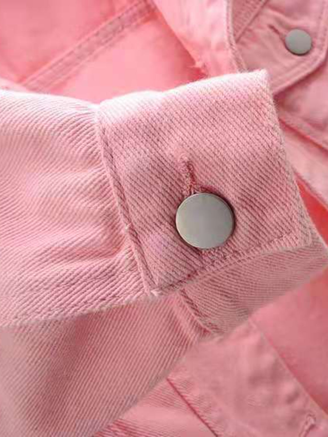 Pink denim trucker jacket detail showing button cuff and stitching.