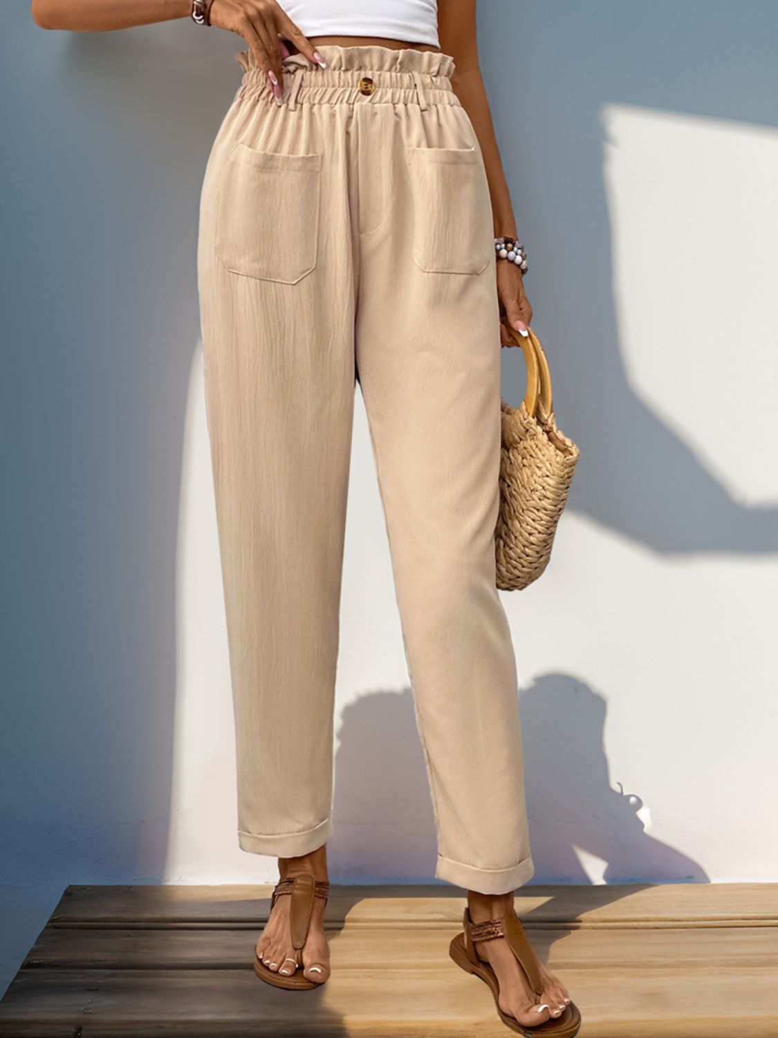 Tan linen blend trousers with gathered waist, button detail, and cuffed hem.