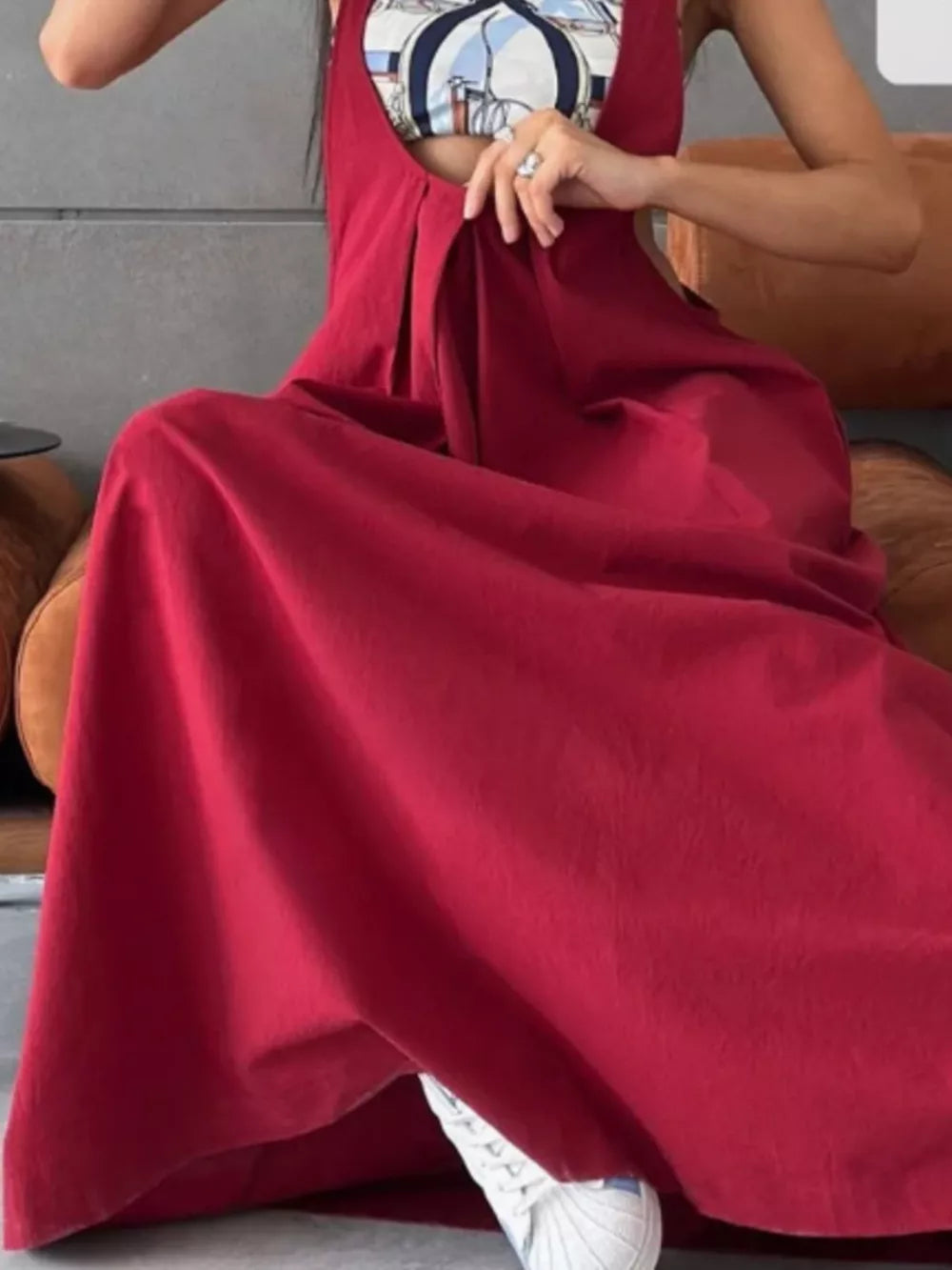 Wine Red pleated overall dress with pockets, shown with a patterned top and sneakers.