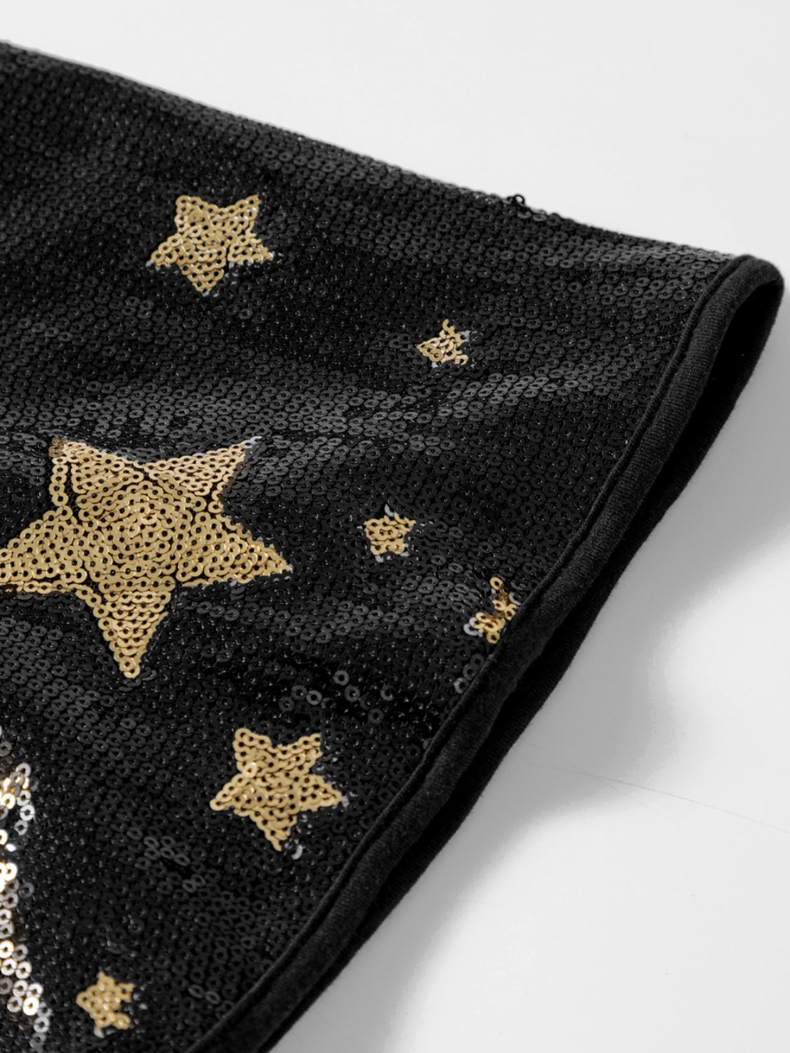 Black knit top with gold sequin stars on the sleeves.