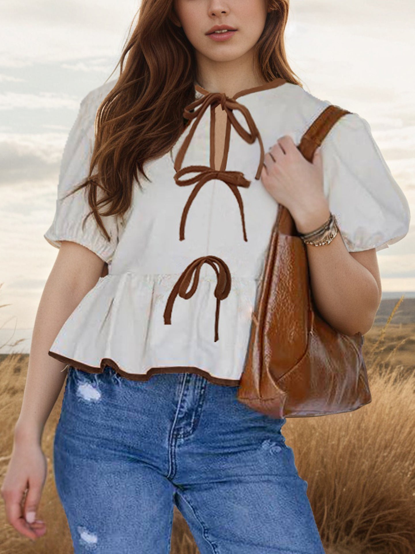 White peplum blouse with puff sleeves, brown trim, and tie details.