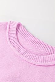 Pink knit sweater with contrast stitching detail on neckline and cuffs.