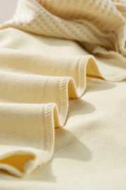 Beige waffle knit sweatshirt detail showing textured fabric and stitching.