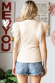 Cream ribbed knit blouse with sheer dot mesh flutter sleeves.