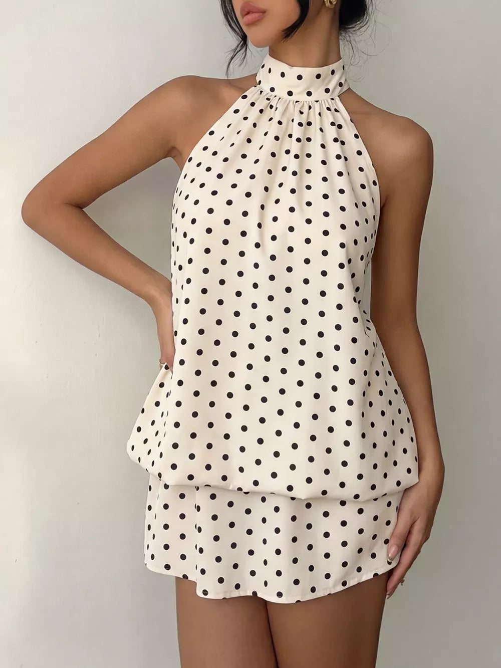 Apricot polka dot halter mini dress with gathered neckline and tiered skirt.