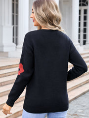 Black V-neck knit sweater with red daisy print on sleeve.