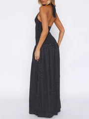 Black polka dot halter neck maxi dress with a backless design and tiered skirt.
