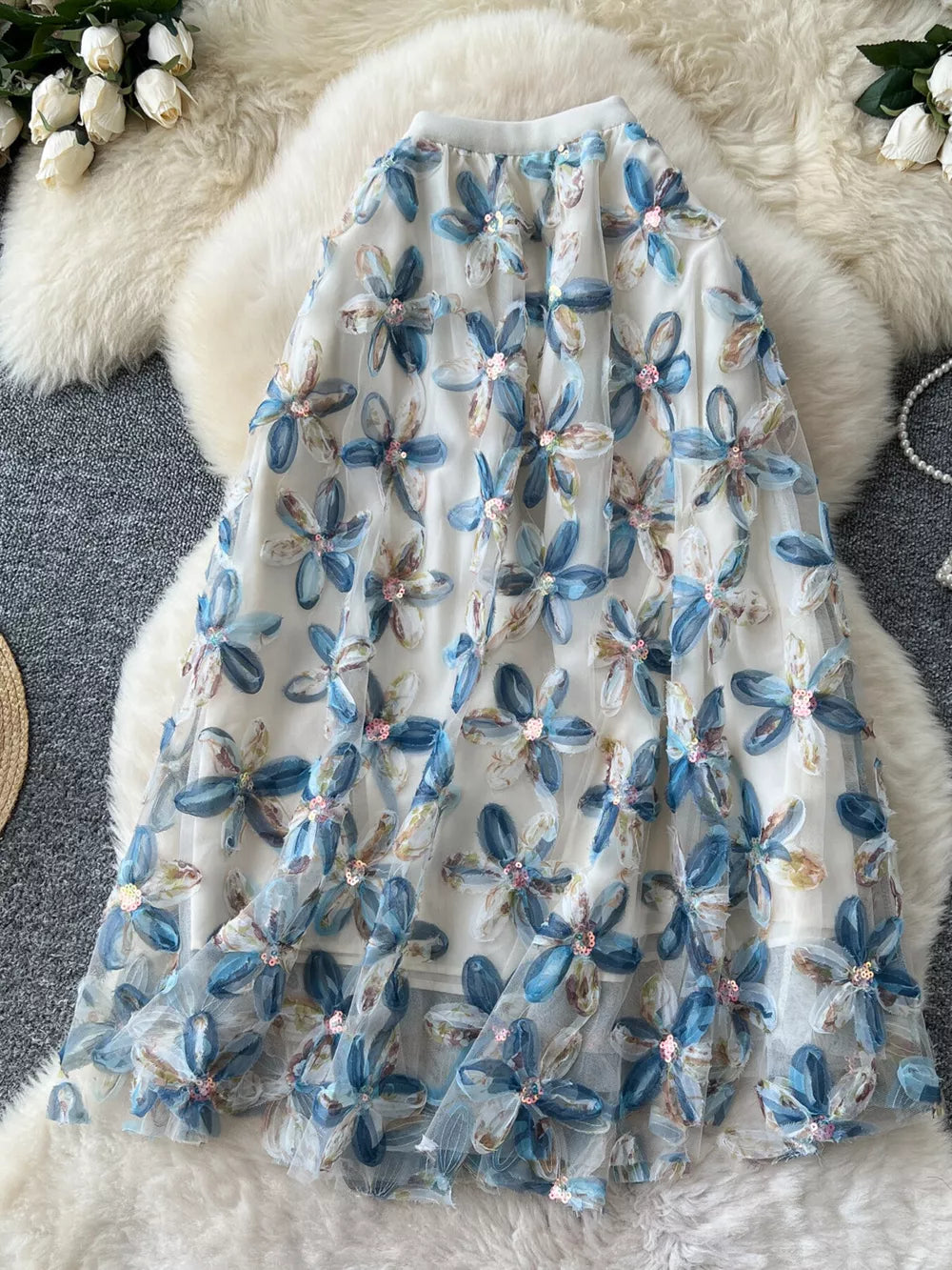 Layered midi skirt with blue floral embroidery and sequins on sheer fabric.