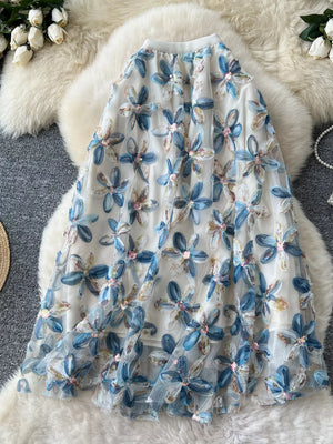 Layered midi skirt with blue floral embroidery and sequins on sheer fabric.
