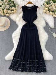 Black knit midi dress with pearl details at neckline, armholes, and hem.