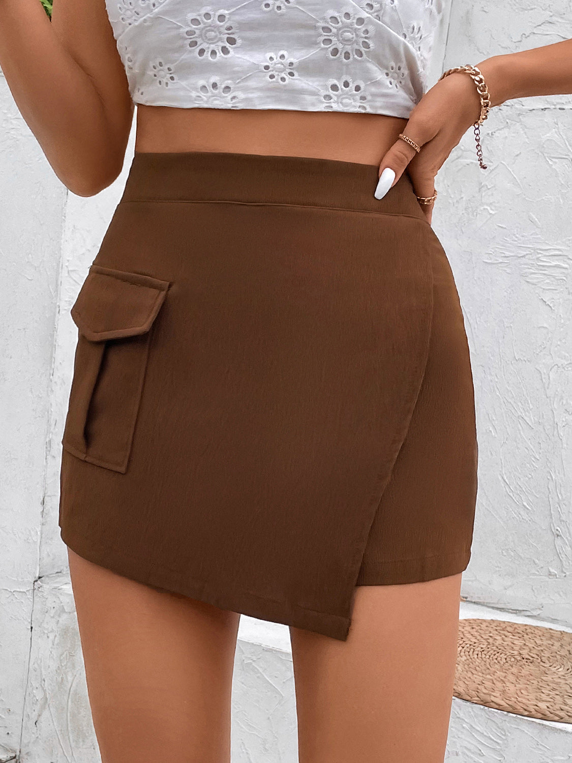 Brown asymmetric wrap-front high-waist shorts with a cargo pocket detail.