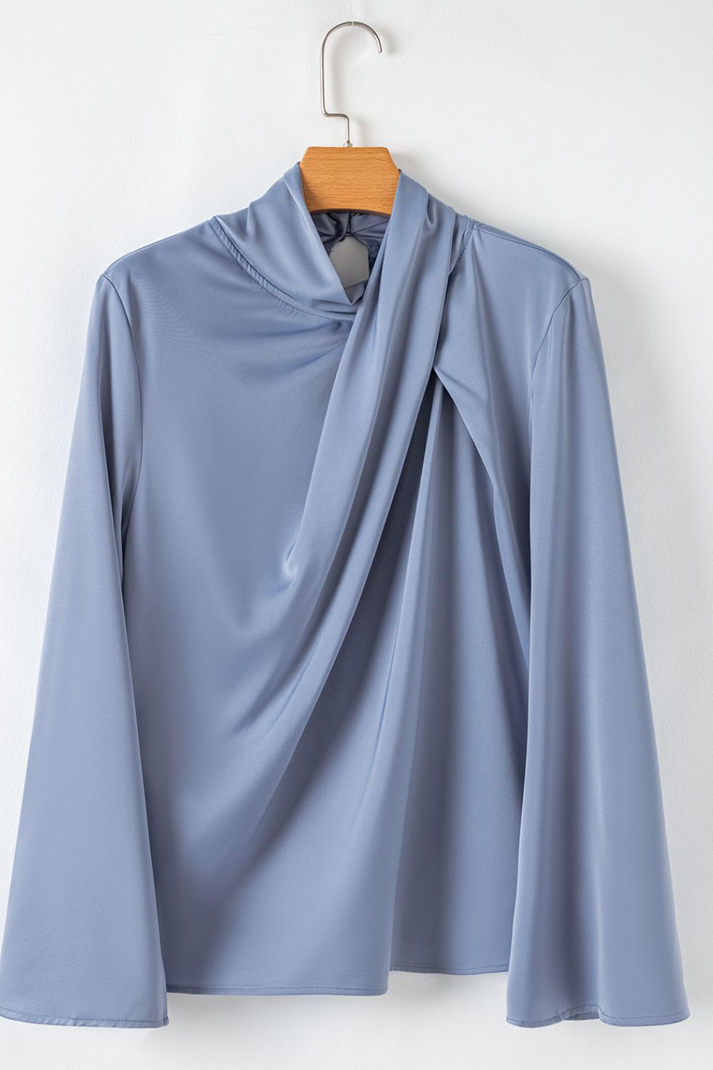 Dusty blue blouse with draped neckline and bell sleeves.