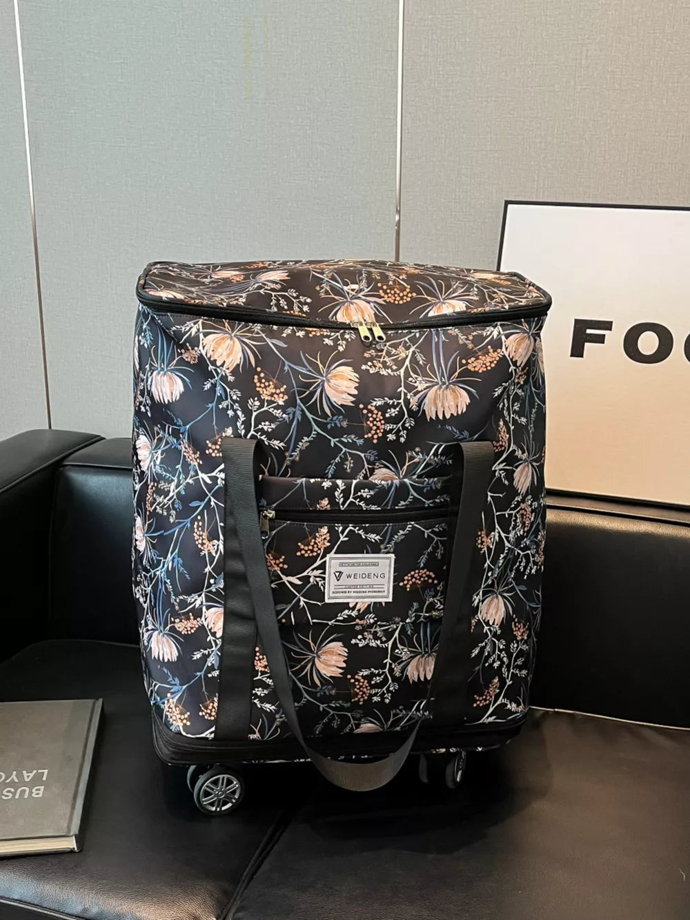 Black floral rolling travel bag with dual zippers and front pocket.