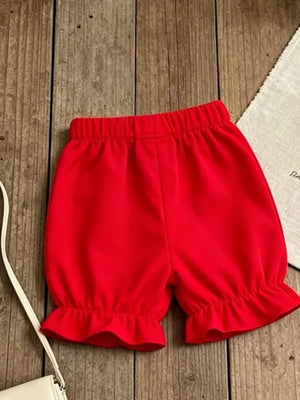 Red baby bloomers with elastic waist and ruffled leg openings.
