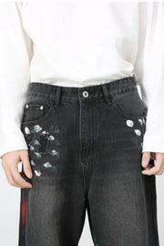 Dark wide-leg jeans with painterly white and green brushstrokes and distressed details.