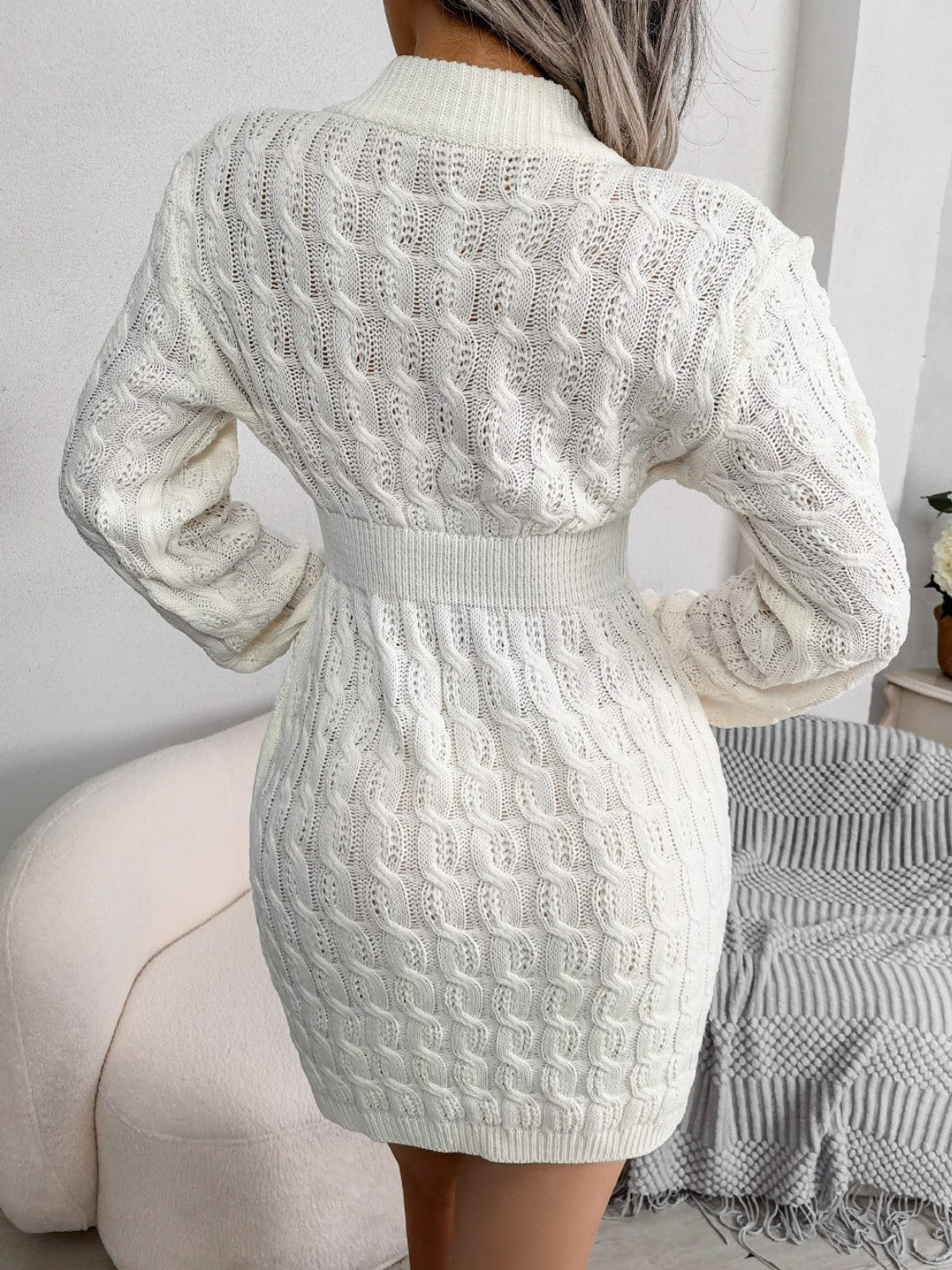 White cable knit mini dress with long sleeves and a high neckline.