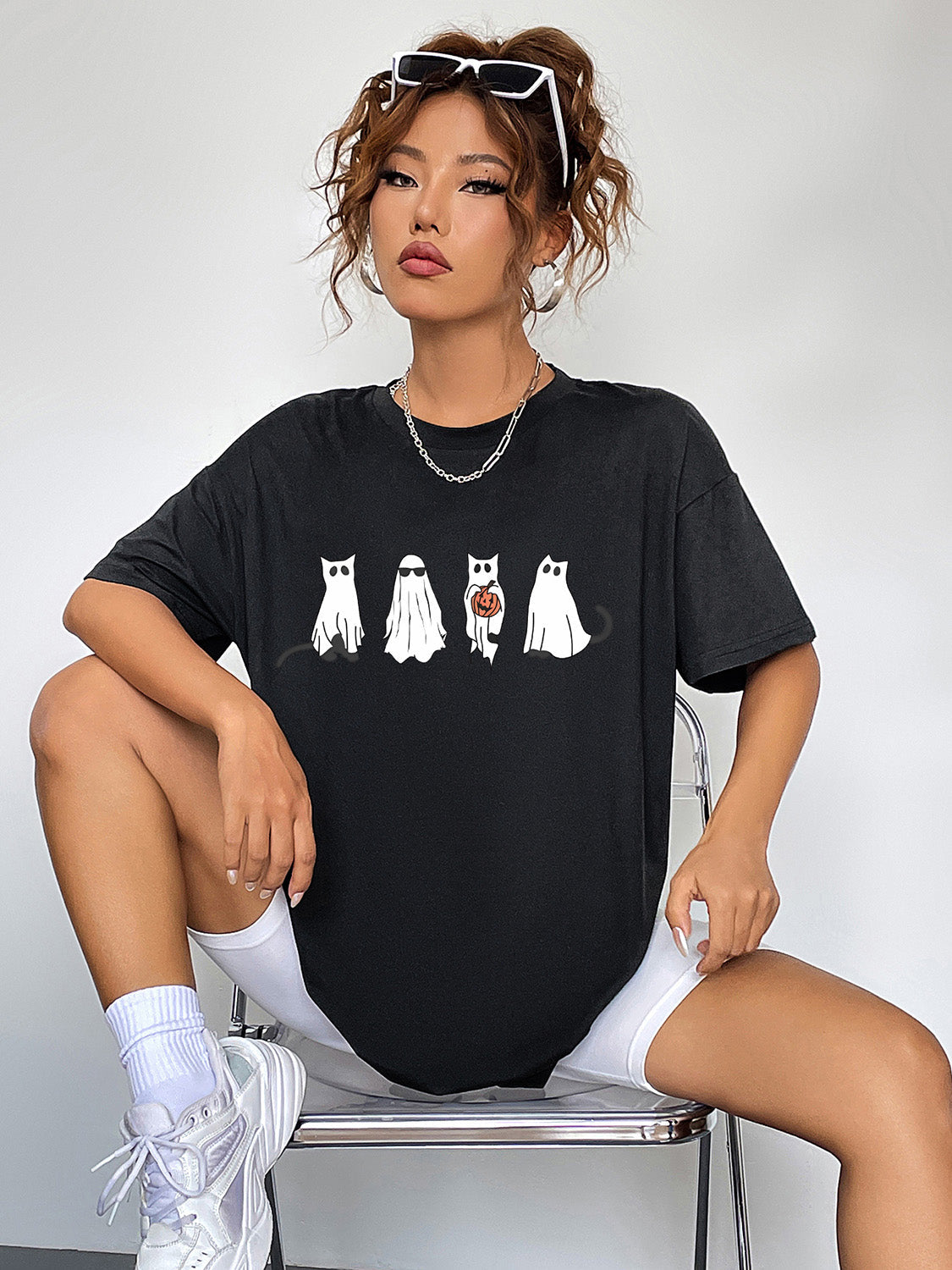 Black crew neck t-shirt with a graphic of five white cats dressed as ghosts, one holding a pumpkin.
