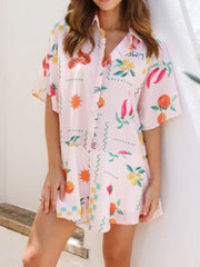 Blush pink romper with fruit and chili pepper print, short sleeves, and buttoned collar.