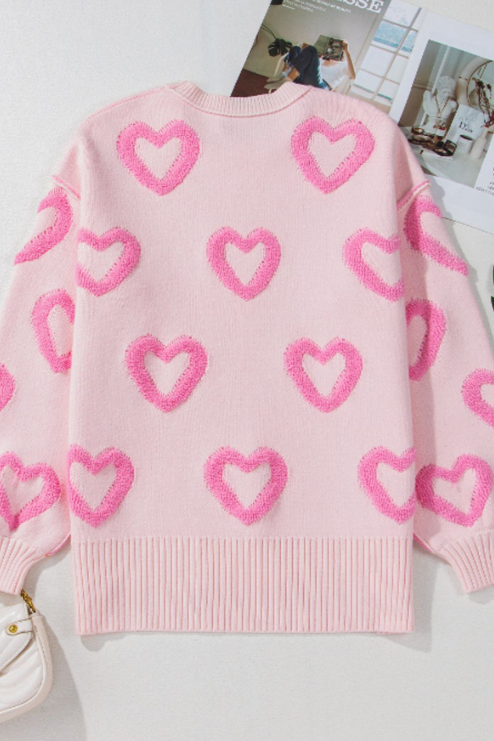 Pink knit sweater with allover textured heart appliques and balloon sleeves.