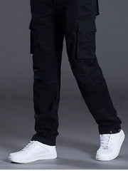 Men's black relaxed fit cargo pants with multiple pockets, styled with white sneakers.