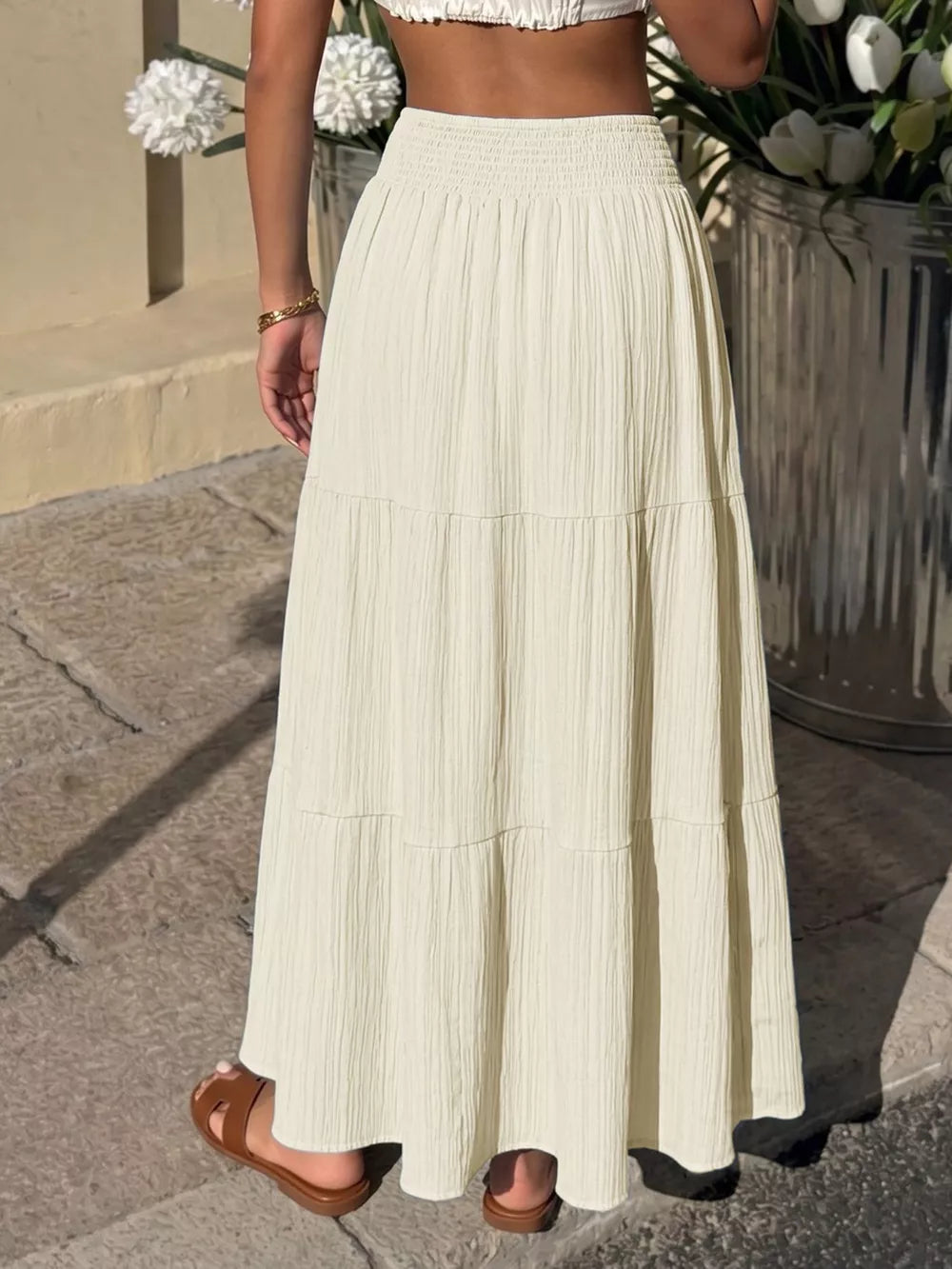 Smocked tiered maxi skirt in apricot with flowing fabric and textured detail.
