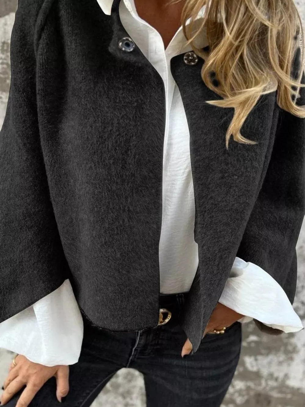 Black fuzzy knit cardigan with button detail, open front, worn over white shirt.