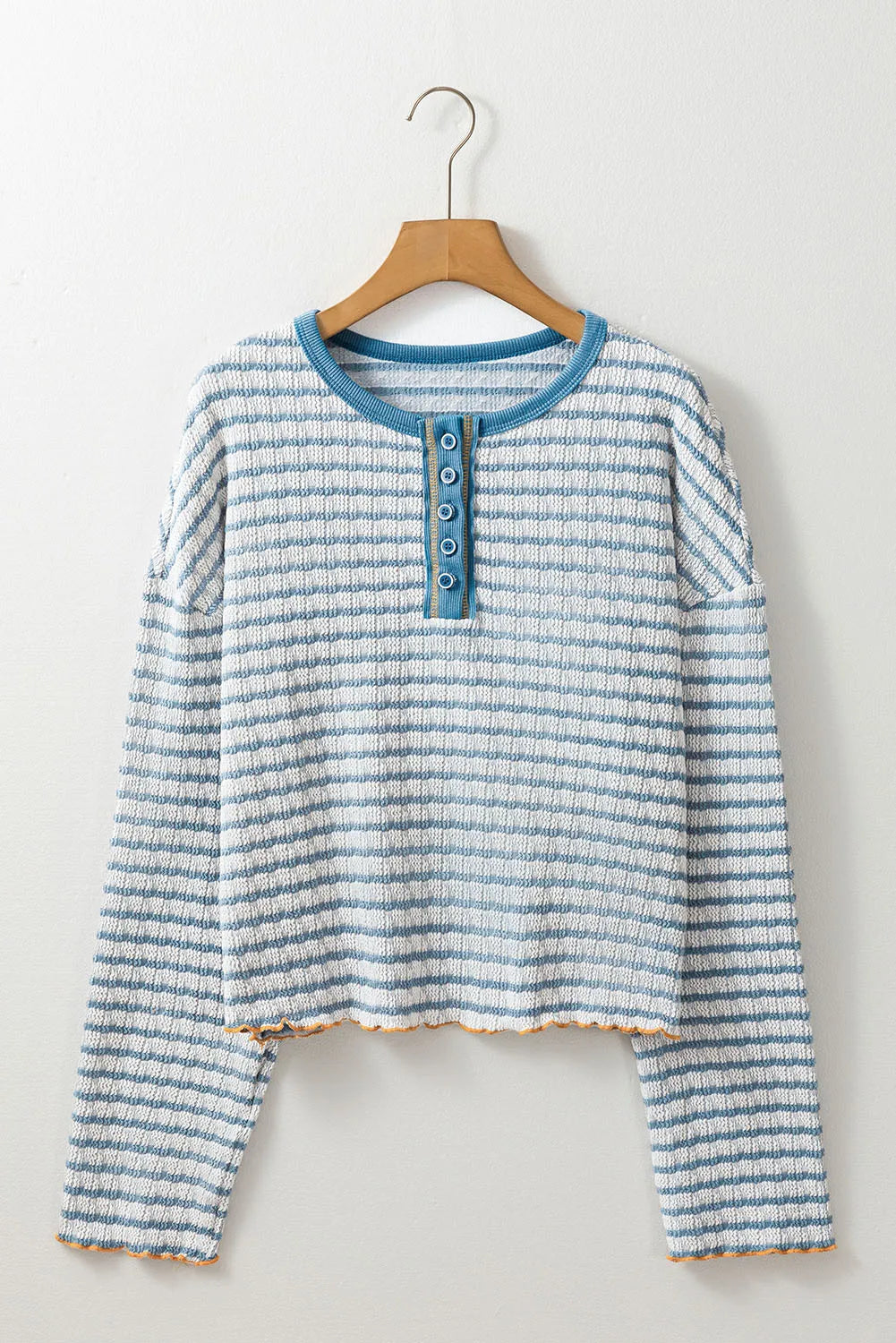Textured stripe henley sweater in dusty blue with button placket and lettuce hem detail.