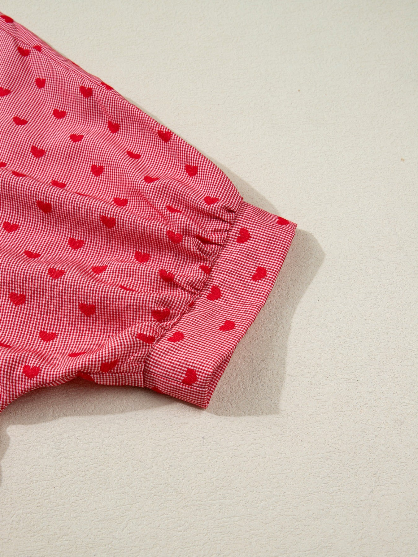 Red gingham button-down shirt with a small red heart pattern and cuffed sleeves.