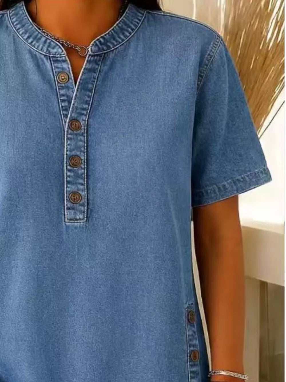 Denim-inspired blue short sleeve button blouse with band collar and side buttons.