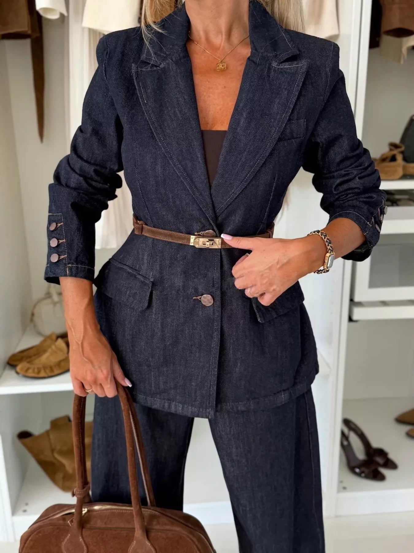 Dark blue denim double-breasted blazer with button cuffs and a brown belt.