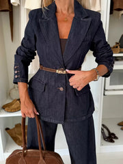 Dark blue denim double-breasted blazer with button cuffs and a brown belt.