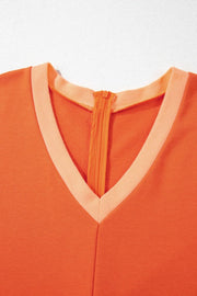 Colorblock V-neck romper in orange with a contrasting trim and zipper detail.