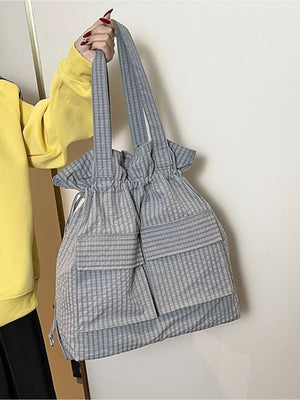 Grey plaid drawstring backpack with front pockets and adjustable straps.