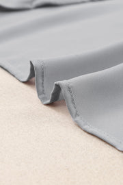 Gray relaxed V-neck blouse with cap sleeves and a soft, flowing fabric.