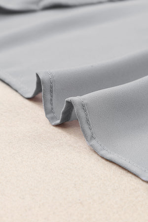 Gray relaxed V-neck blouse with cap sleeves and a soft, flowing fabric.