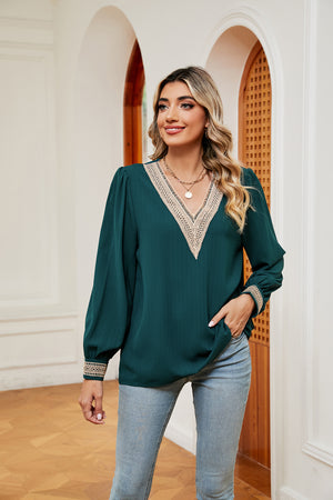 Green V-neck blouson top with embroidered trim on neckline and cuffs.
