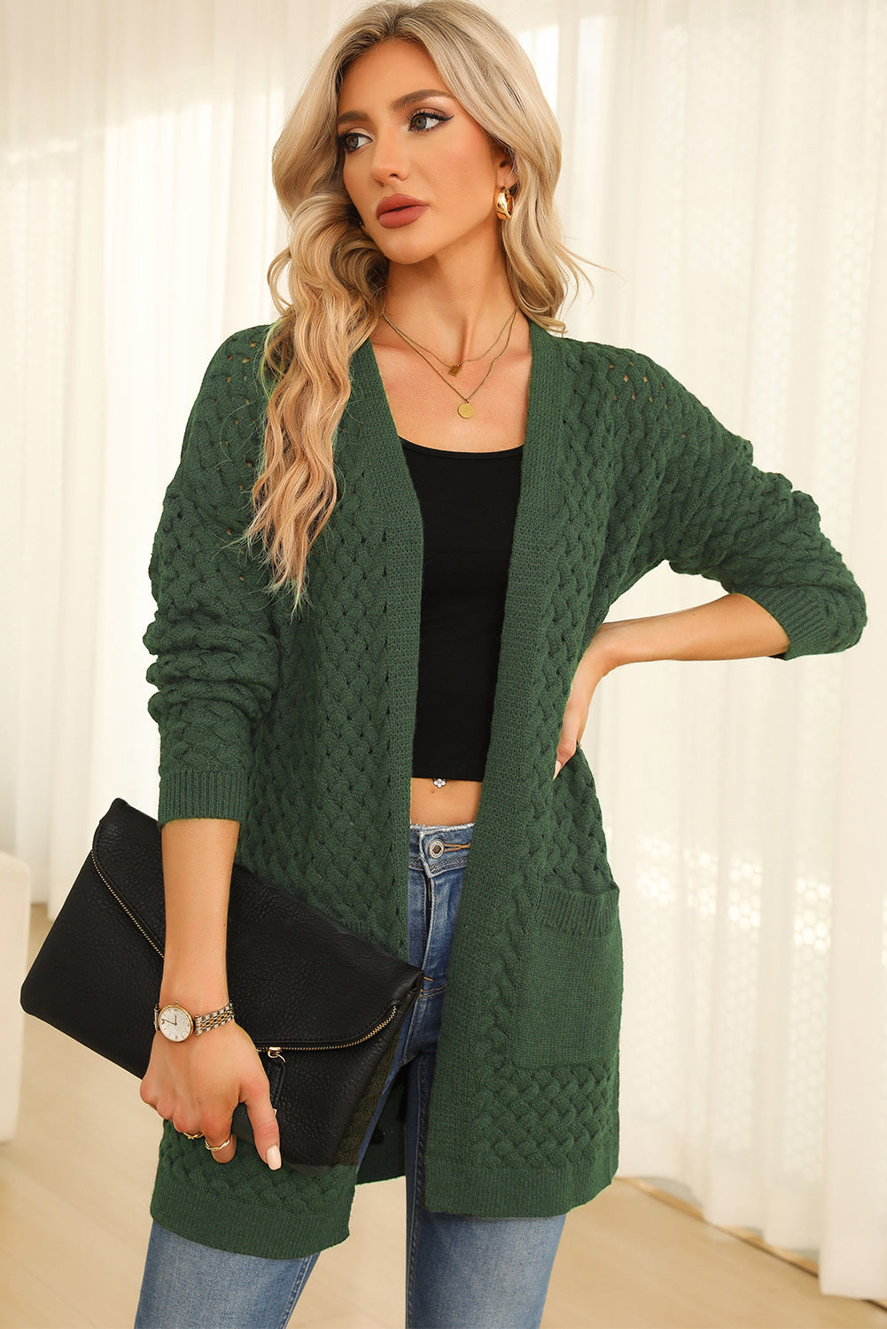 Dark green open-knit pocket cardigan with textured cable knit details and long sleeves.