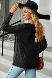 Black V-neck blouse with diamond texture and button cuff detail.