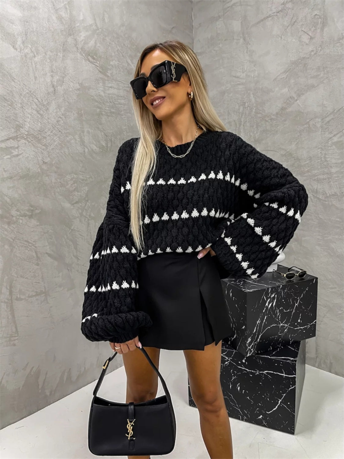 Black knit sweater with textured stripes and balloon sleeves, styled with a black skirt.