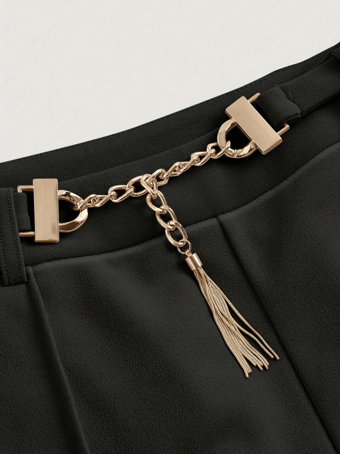 Black flared leg trousers with gold chain detail and tassel accent.
