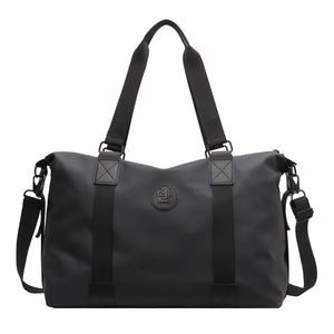 Black canvas duffel bag with dual handles, adjustable shoulder strap, and embossed logo.