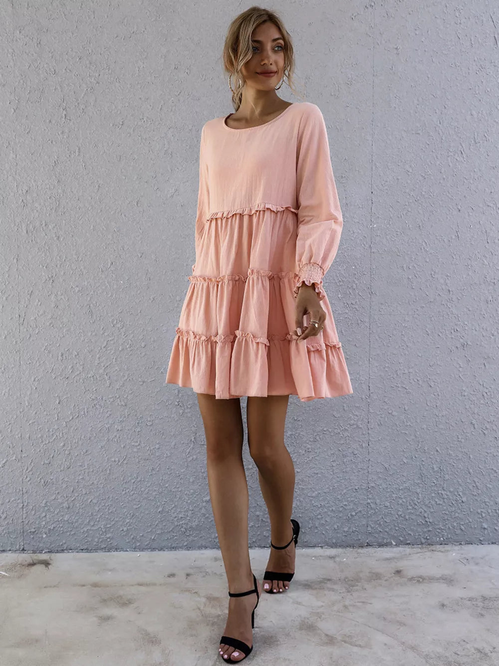 Apricot ruffled mini dress with long sleeves and tiered skirt.