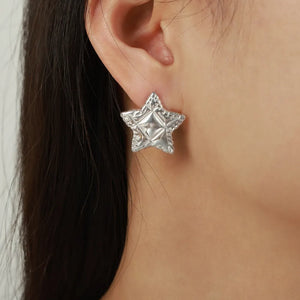 Textured celestial star stud earrings in silver with a detailed surface.
