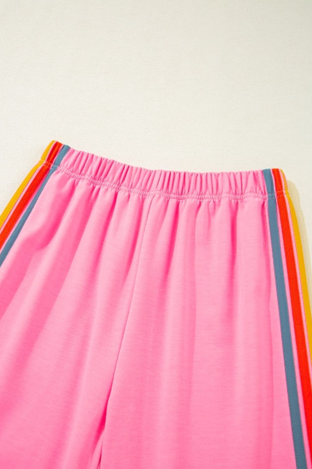 Pink track pants with rainbow stripe detail on side