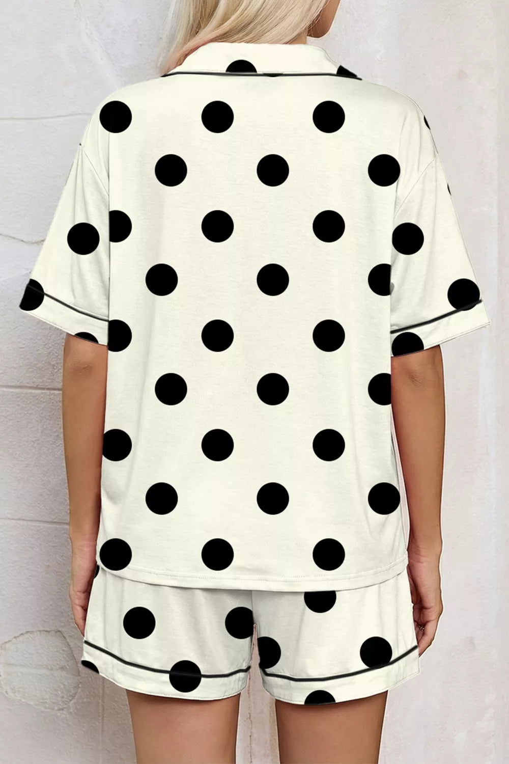 Cream polka dot pajama set with button-up top and shorts, featuring black piping detail.