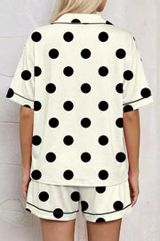 Cream polka dot pajama set with button-up top and shorts, featuring black piping detail.