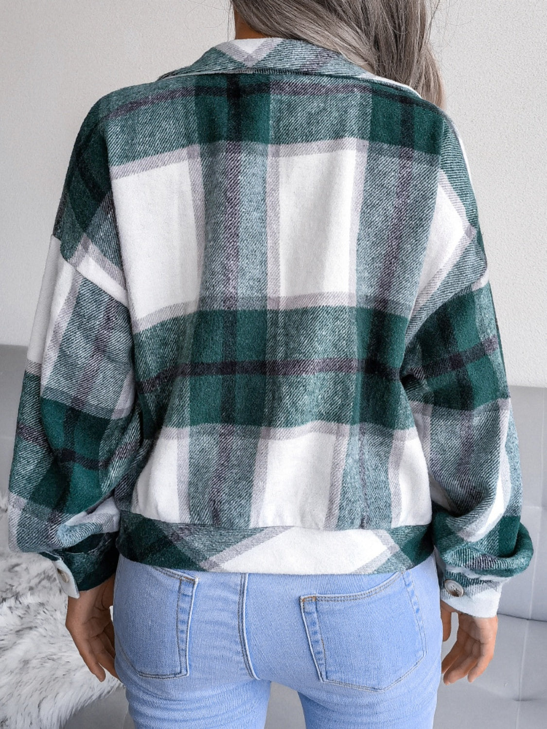 Oversized dark green tartan shacket with buttoned cuffs and collar, worn with jeans.