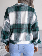 Oversized dark green tartan shacket with buttoned cuffs and collar, worn with jeans.