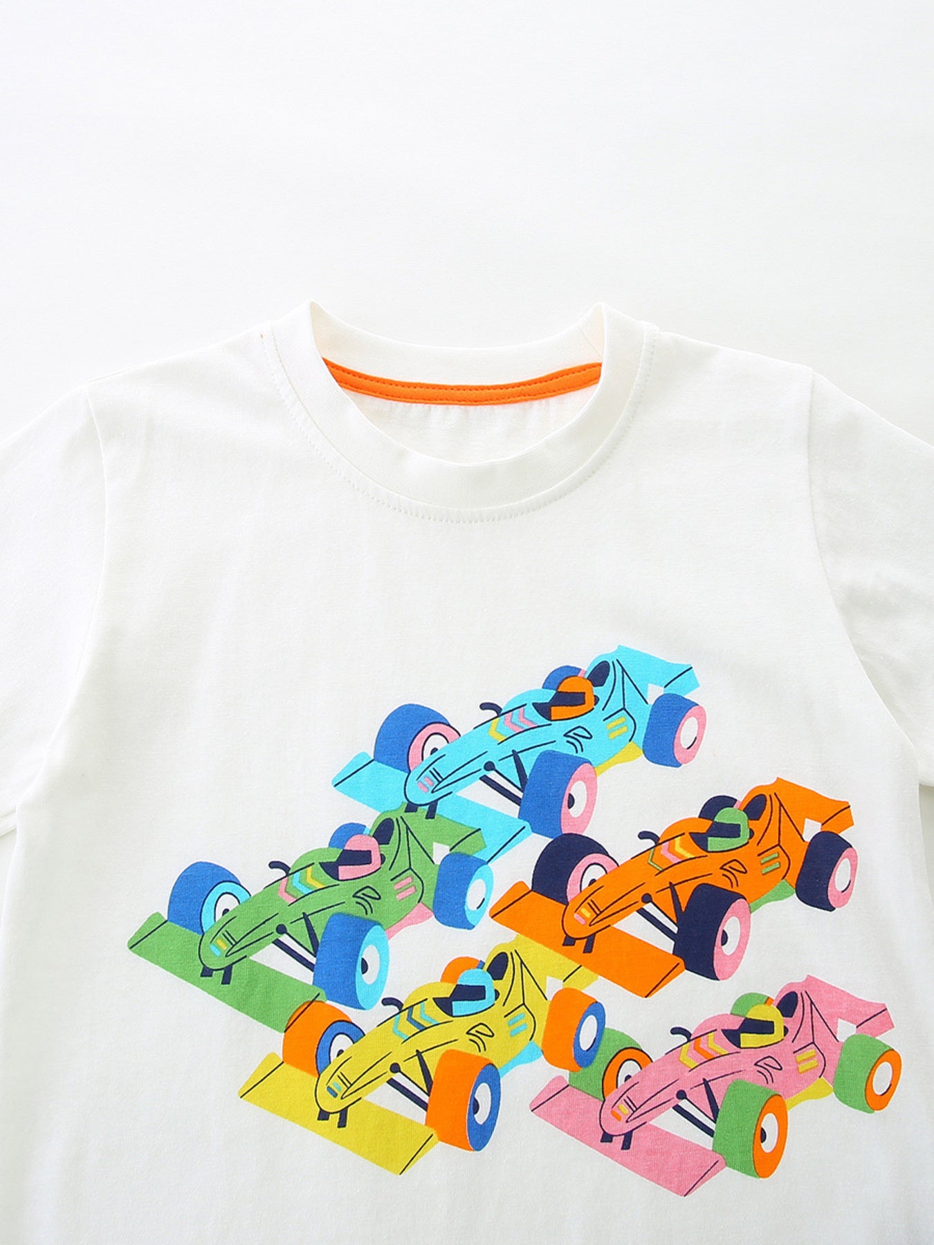 White 100% cotton t-shirt with colorful racing car graphic and orange neckline trim.