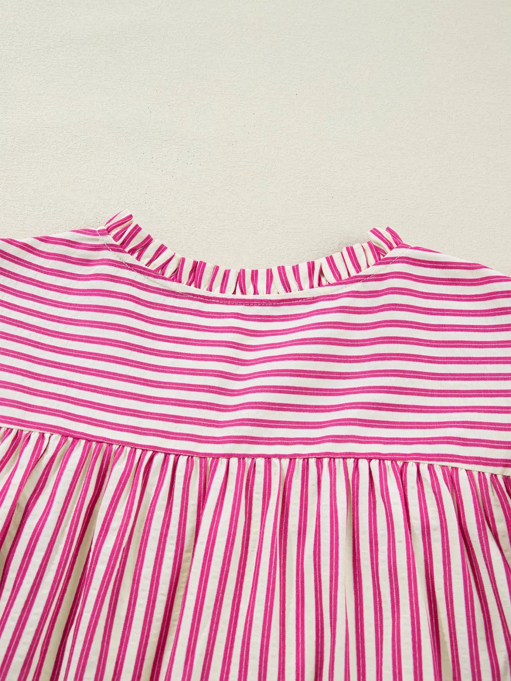 Maternity blouse with pink and white stripes, ruffled neckline, and shirred yoke.